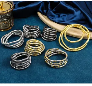 Detail of bendable snake jewelry in various metallic finishes on a blue surface