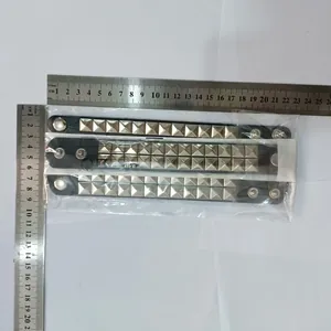 Top view of three punk studded leather bracelets in packaging with measuring rulers