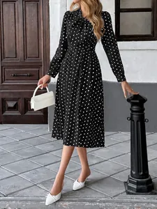 Détail d'une élégante robe midi à pois noirs avec col à nœud papillon et manches longues