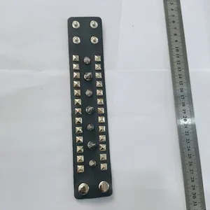 Black PU leather punk bracelet with silver studs and spikes next to a metal ruler