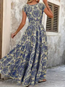 Back view of a vintage blue printed maxi dress with smocked waist in rustic setting