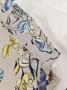 Close-up detail of elegant floral print and neat hem stitching on a women's dress.