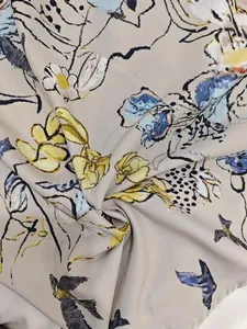 Detail view showing elegant floral and bird print on beige spring dress fabric
