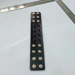 Gros plan sur un bracelet manchette punk en cuir noir avec clous et pointes argentés