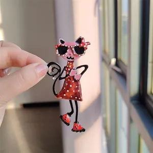Close-up of a cute polka dot cat enamel brooch with sunglasses held by a hand in sunlight