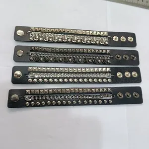 Gros plan de quatre bracelets en cuir noir style punk avec clous et chaînes métal.