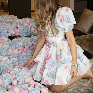 Close-up detail view of an elegant floral tiered dress with puff sleeves and deep V-neck.