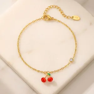 Detailed close-up of an elegant 18K gold plated cherry charm bracelet on marble base