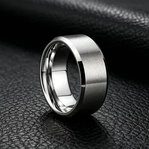 Detailopname van een zilveren geborstelde titanium stalen ring op zwart lederen textuur.