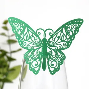 Détail d'une décoration de carte papillon verte ajourée sur le rebord d'un verre