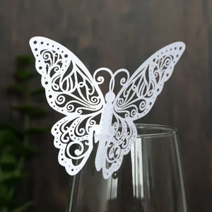Gros plan d'une carte papillon 3D creuse découpée au laser blanche sur le bord d'un verre