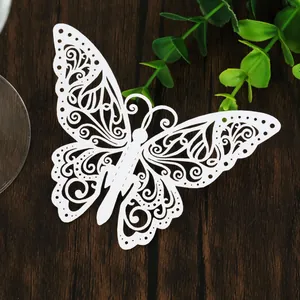 Gros plan d'un papillon creux découpé au laser blanc sur une surface en bois sombre.