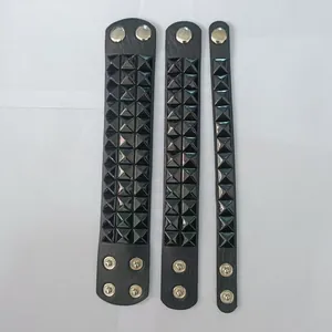 Detail of three black leather punk bracelets with pyramid studs and silver snaps