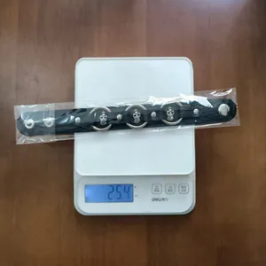 Punk style black leather bracelet with silver skulls, weighing 25.4g on a digital scale.
