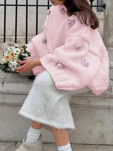 Close-up detail of a pink chunky knit sweater featuring delicate 3D lavender floral appliqués.