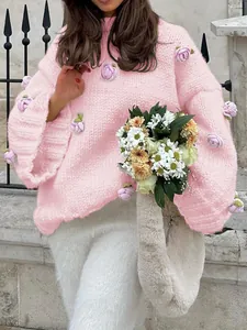 Detailed close-up of pink chunky knit sweater featuring delicate 3D floral appliques