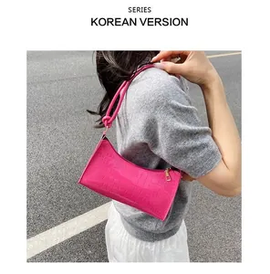 Hot pink crocodile embossed texture baguette shoulder bag carried on a model's shoulder