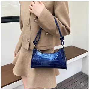 Elegant glossy blue crocodile pattern shoulder bag styled with beige skirt suit on model