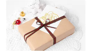 Gros plan d'une boîte cadeau en kraft avec un ruban de Noël festif et une carte.