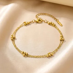 Elegant double-layered stainless steel anklet with delicate gold beads on silk.