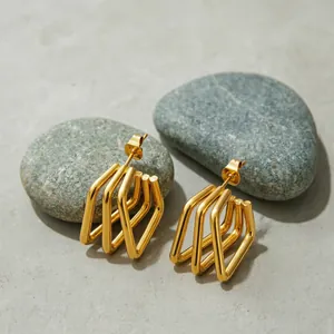 Elegant gold stainless steel earrings with geometric lines displayed on grey river stones