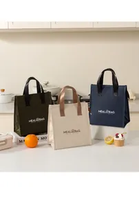 Three minimalist insulated meal bags in green, beige and navy blue displayed in a kitchen