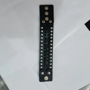 Detail view of a black braided leather punk bracelet featuring silver studs and snaps