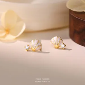 Macro view of iridescent shell stud earrings with sparkling zircon accents.