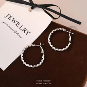 Close-up of S999 silver hoop earrings with colorful cubic zirconia on brown velvet
