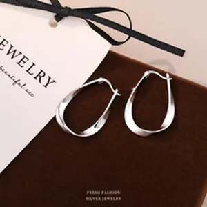 Detailed macro view of S999 sterling silver twisted hoop earrings on brown velvet padding
