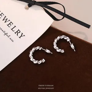 Detail shot of elegant S999 sterling silver twisted hoop earrings on velvet