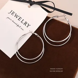 Close-up view of elegant double-layer silver hoop earrings on a dark velvet display