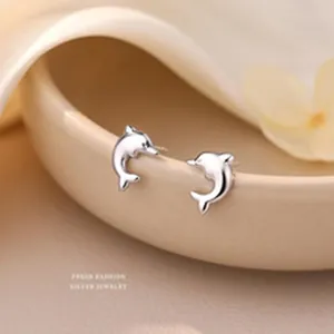 Macro detail of elegant s999 sterling silver dolphin stud earrings in a warm setting