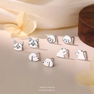 Close-up detail of cute white enamel animal-head silver stud earrings on a beige background