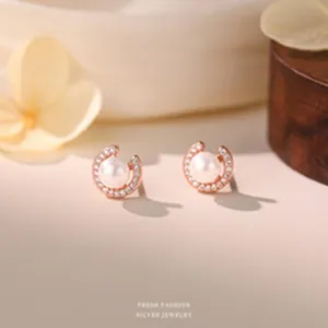 Macro view of dainty S999 silver stud earrings with sparkling zircon and round pearls