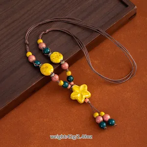 Detailed view of handmade ethnic ceramic necklace with a vibrant yellow flower pendant
