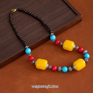 Close-up of ethnic style ceramic sweater chain with large yellow beads and red accents