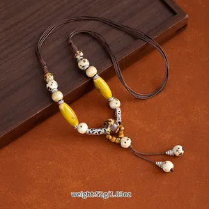Detailed shot of an ethnic style ceramic beaded long necklace on a dark wood tray background.