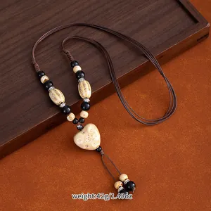 Close-up of ethnic style ceramic heart pendant necklace with beads on a dark wooden tray