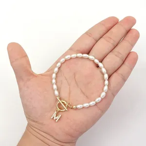 Elegant oval pearl bead bracelet with rhinestone initial M pendant on a hand