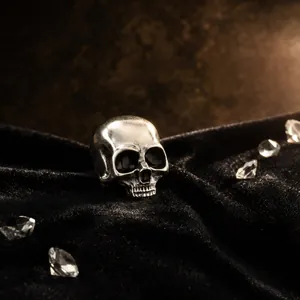 Close-up of vintage silver skull brooch on black velvet background with crystals