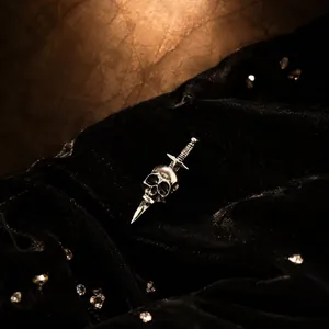 Detailed close-up of a gothic vintage silver skull and dagger brooch on black velvet