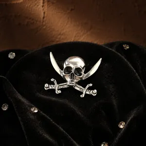 Detailed view of a vintage silver pirate skull brooch with cross swords on black velvet