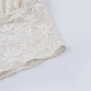 Détail en gros plan de la dentelle blanche avec motifs floraux floqués pour un haut d'été