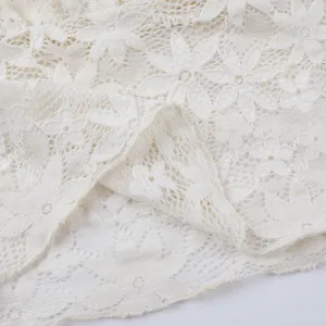 Détail en gros plan montrant la texture délicate de la dentelle florale blanche floquée