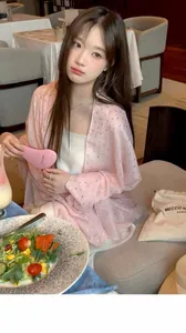 Model wearing a pink sheer rhinestone shawl in a lifestyle cafe setting detail view.
