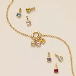 Close-up detail of a delicate gold chain featuring multiple vibrant square gemstone charms