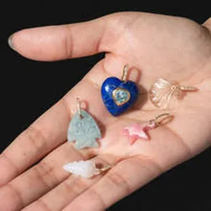 Close-up detail of various colorful resin and stone jewelry pendants held in a hand