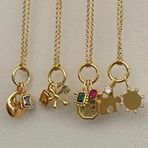 Detailed view of multiple gold charm necklaces featuring moon, bow, and puzzle pendants