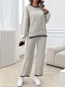 Full body view of a beige knitted two-piece set with striped trim on a model